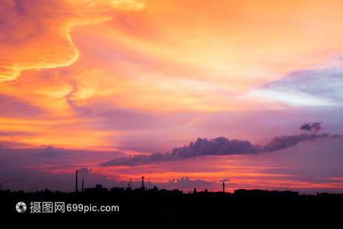 城市工業景色與日落背與城市建筑和有煙氣的工廠管道輪光相伴